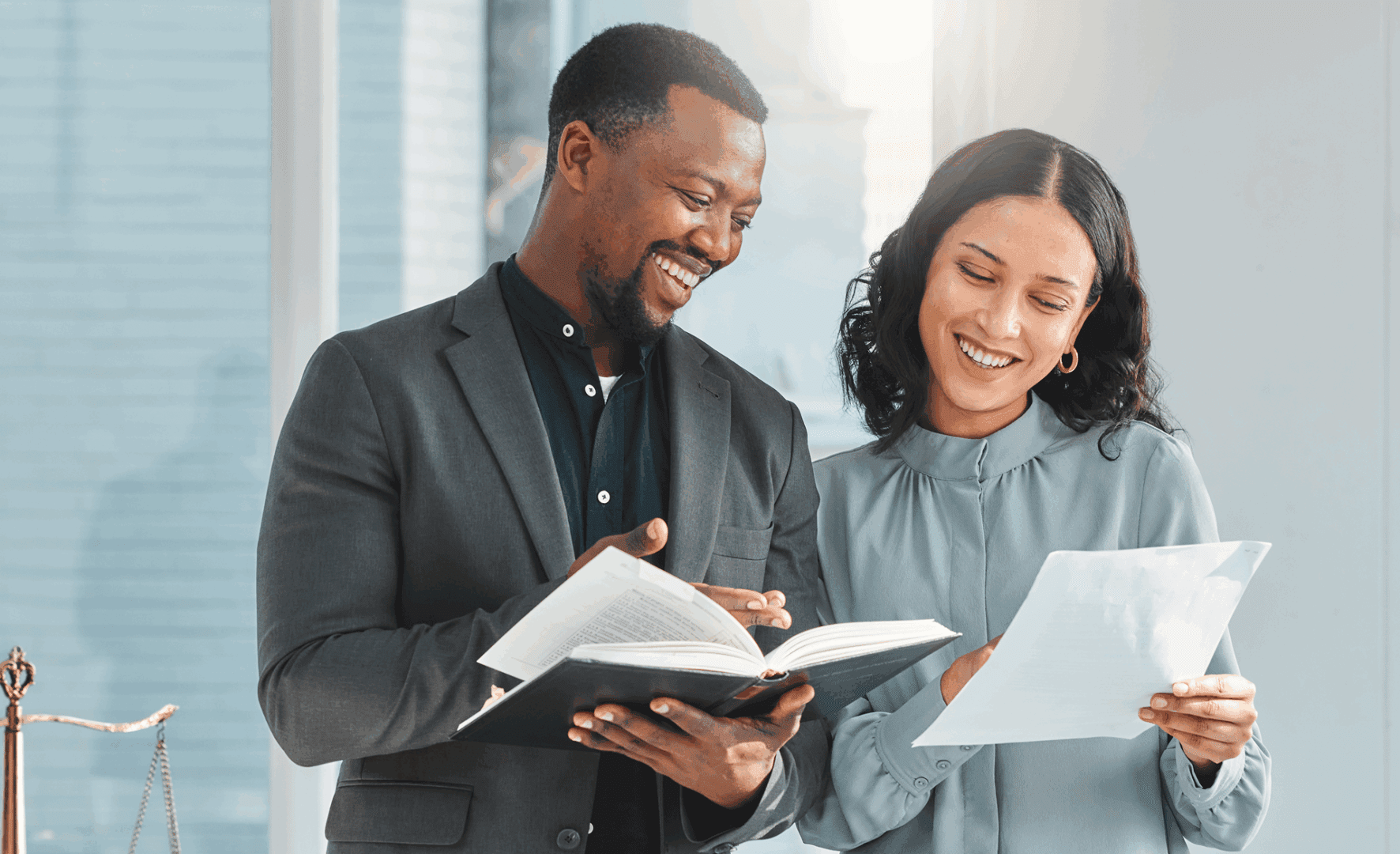 Two colleagues happily reviewing documents together in an office.
