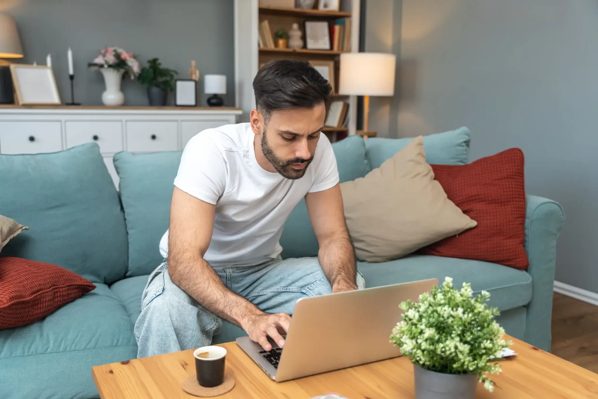 Man focused on laptop while sitting on sofa in cozy living room.