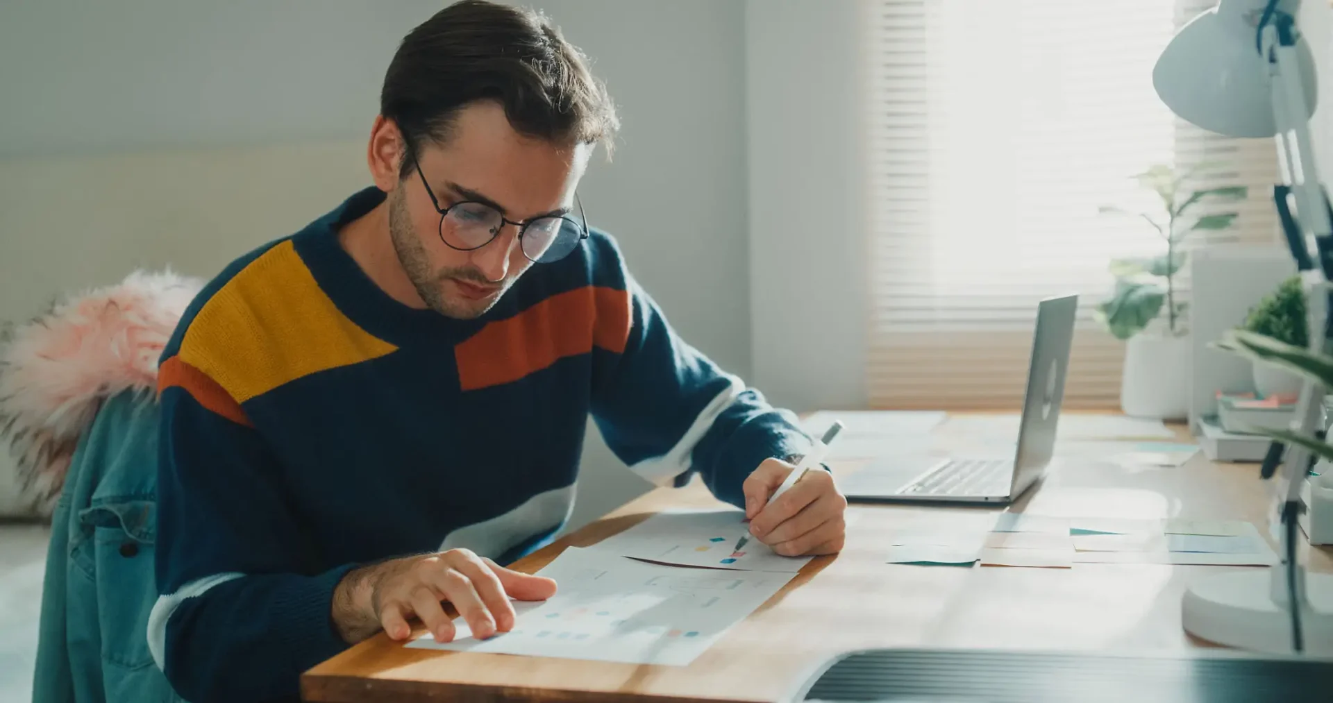 Man focused on drawing architectural plans at a desk.