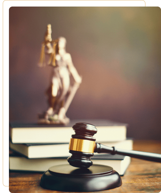 Judge's gavel and law books with Lady Justice statue in the background.