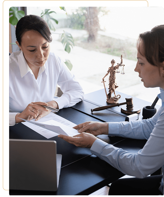 Two professionals reviewing a document in an office with a justice scale on the desk.
